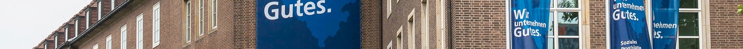 Foto vom LWL-Landeshaus in Münster mit Fahnen und Fassadenbanner mit LWL-Slogan "Wir unternehmen Gutes."